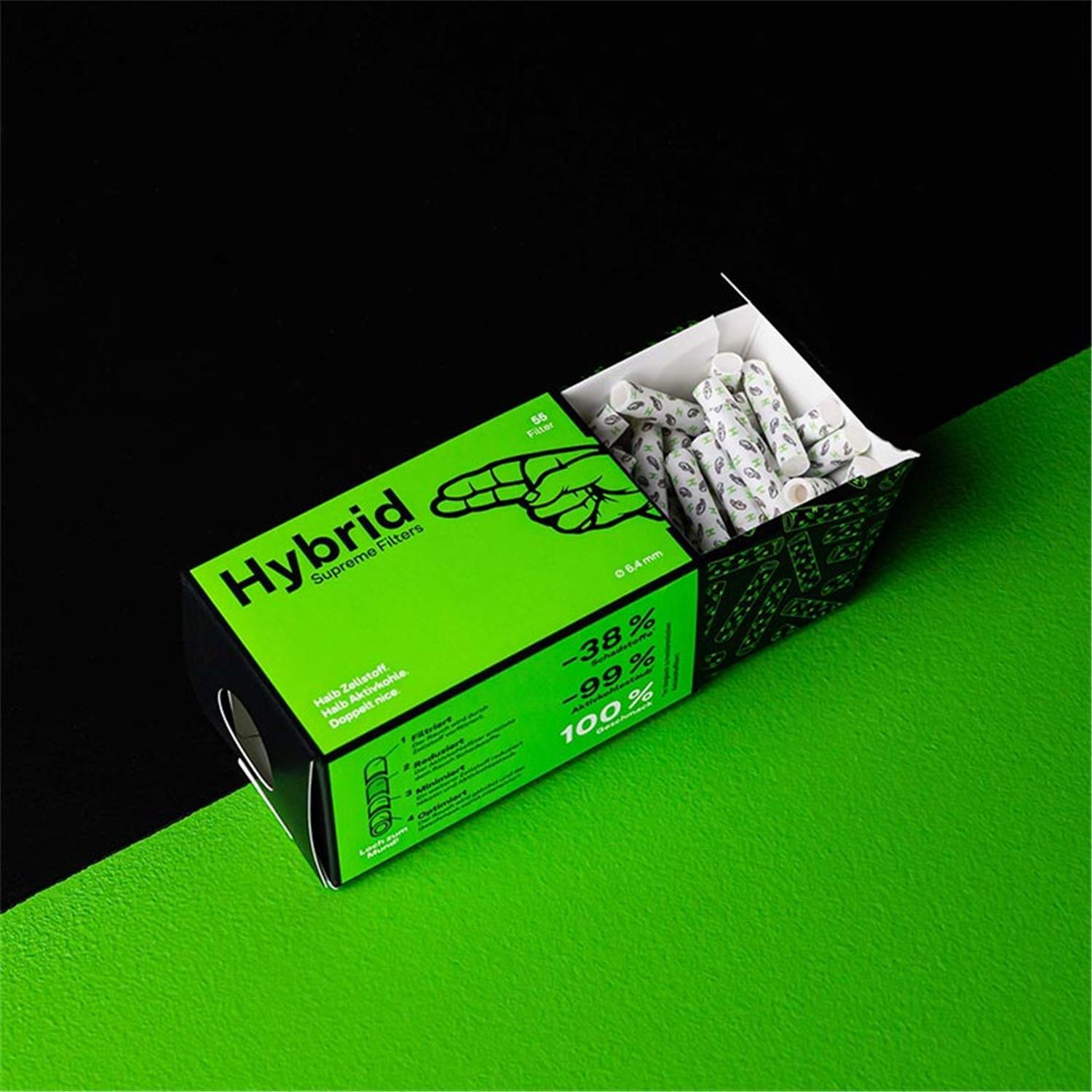 Hybrid Supreme Filters 55er Faltschachtel – geöffnete schwarz-grüne Zigarettenschachtel-förmige Verpackung mit Hand-Illustration, sichtbare weiß-graue Filter im Inneren, seitliche Aufschriften "Halb Zellstoff. Halb Aktivkohle. Doppelt nice.", -38% Schadstoffe, -99% Aktivkohlestaub, 100% Geschmack, Ø 6,4mm, vor schwarzem Hintergrund auf grüner Fläche